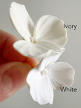 Load image into Gallery viewer, Two white flowers, one labeled 'Ivory' and the other 'White', held by a hand against a gray background.