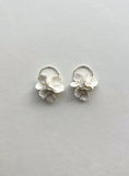 Load image into Gallery viewer, Pair of silver flower-shaped earrings on a light gray background