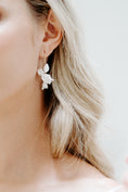 Load image into Gallery viewer, Close-up of a person wearing a floral earring with a blurred background