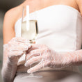 Load image into Gallery viewer, Person in a white dress holding a glass of champagne with lace bridall gloves.