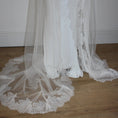 Charger l'image dans la visionneuse de la galerie, White lace veil and wedding dress on a wooden floor with a plain white wall background
