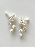 Load image into Gallery viewer, Pair of white floral earrings on a light gray background