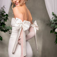 Load image into Gallery viewer, Woman wearing a white off-shoulder dress with opera gloves with large bows in a softly blurred setting.