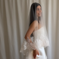 Charger l'image dans la visionneuse de la galerie, Bride wearing a white wedding dress with a lace veil against a white curtain background.