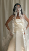 Load image into Gallery viewer, Bride wearing a white wedding dress with a lace veil against a white curtain background.