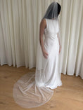 Load image into Gallery viewer, Person wearing a white wedding dress with a long plain veil against a plain background