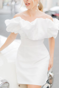 Load image into Gallery viewer, a woman wearing a white off-shoulder dress against a city background wearing silk flower bridal earrings