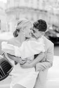 Load image into Gallery viewer, a married couple with the woman wearing a white off-shoulder dress against a city background wearing silk flower bridal earrings