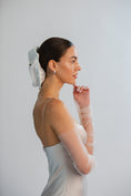 Load image into Gallery viewer, Woman in a white dress with sheer sleeves against a white background
