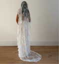 Load image into Gallery viewer, Person wearing a white wedding dress with a long lace veil against a plain background