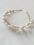 Load image into Gallery viewer, Gold headband with white floral embellishments on a light background