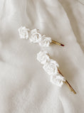 Load image into Gallery viewer, Two white floral hairpins on a white fabric background