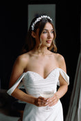 Load image into Gallery viewer, Woman in a white wedding dress holding a glass of champagne, wearing a floral headband.