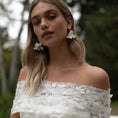 Load image into Gallery viewer, Woman wearing an off-shoulder white dress with floral details outdoors.