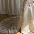 Charger l'image dans la visionneuse de la galerie, Bride wearing a white wedding dress with a lace veil against a white curtain background.