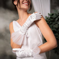 Load image into Gallery viewer, Woman wearing a white one-shoulder dress with a large bow and white gloves against a blurred background.