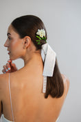 Load image into Gallery viewer, Woman with a floral hair accessory and white bridal bow in her hair against a plain background