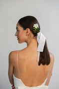 Load image into Gallery viewer, Woman with a floral hair accessory and white bridal bow in her hair against a plain background