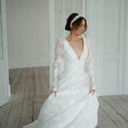 Load image into Gallery viewer, Woman in a white wedding dress standing in a room with wooden flooring.