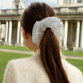 Load image into Gallery viewer, Woman with a decorative bridal hair scrunchie in her ponytail, standing in front of a classical building.