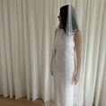 Charger l'image dans la visionneuse de la galerie, Person wearing a white wedding dress with a long pearl veil against a plain background