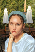 Load image into Gallery viewer, Woman wearing a light blue bridal headband in an outdoor setting with tables and umbrellas.