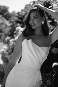 Load image into Gallery viewer, Woman in a white dress standing outdoors with trees in the background