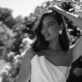 Load image into Gallery viewer, Woman in a white dress standing outdoors with trees in the background