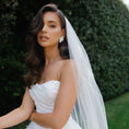 Load image into Gallery viewer, Woman in a white wedding dress with a veil standing outdoors.