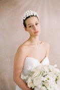 Load image into Gallery viewer, Bride wearing a floral headpiece and holding a bouquet against a beige background