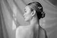 Load image into Gallery viewer, Black and white portrait of a woman with a floral hair accessory against a draped fabric background