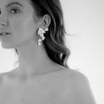 Load image into Gallery viewer, Woman wearing floral earrings with a plain background