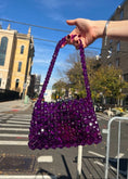 Load image into Gallery viewer, Purple beaded bidal handbag held by a person outdoors with buildings and street in the background