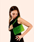 Load image into Gallery viewer, Woman holding a green beaded bridal bag against a beige background