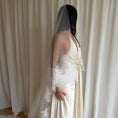 Load image into Gallery viewer, Bride wearing a white wedding dress with a lace veil against a white curtain background.