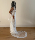 Charger l'image dans la visionneuse de la galerie, Model wearing White lace veil and wedding dress on a wooden floor with a plain white wall background