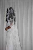 Load image into Gallery viewer, Person wearing a white wedding dress with a long lace veil against a plain background