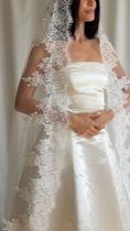 Load image into Gallery viewer, Bride wearing a white wedding dress with a lace veil against a white curtain background.