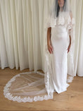 Load image into Gallery viewer, White wedding dress with a long lace veil in front of a white curtain.