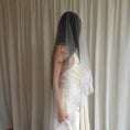 Charger l'image dans la visionneuse de la galerie, Bride wearing a white wedding dress with a lace veil against a white curtain background.