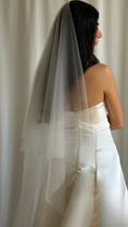 Load image into Gallery viewer, Bride wearing a white wedding dress with a plain veil against a white curtain background.