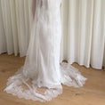 Charger l'image dans la visionneuse de la galerie, White lace veil and wedding dress on a wooden floor with a plain white wall background