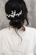 Load image into Gallery viewer, Back view of a person with a decorative hairpiece wearing a white top against a gray background
