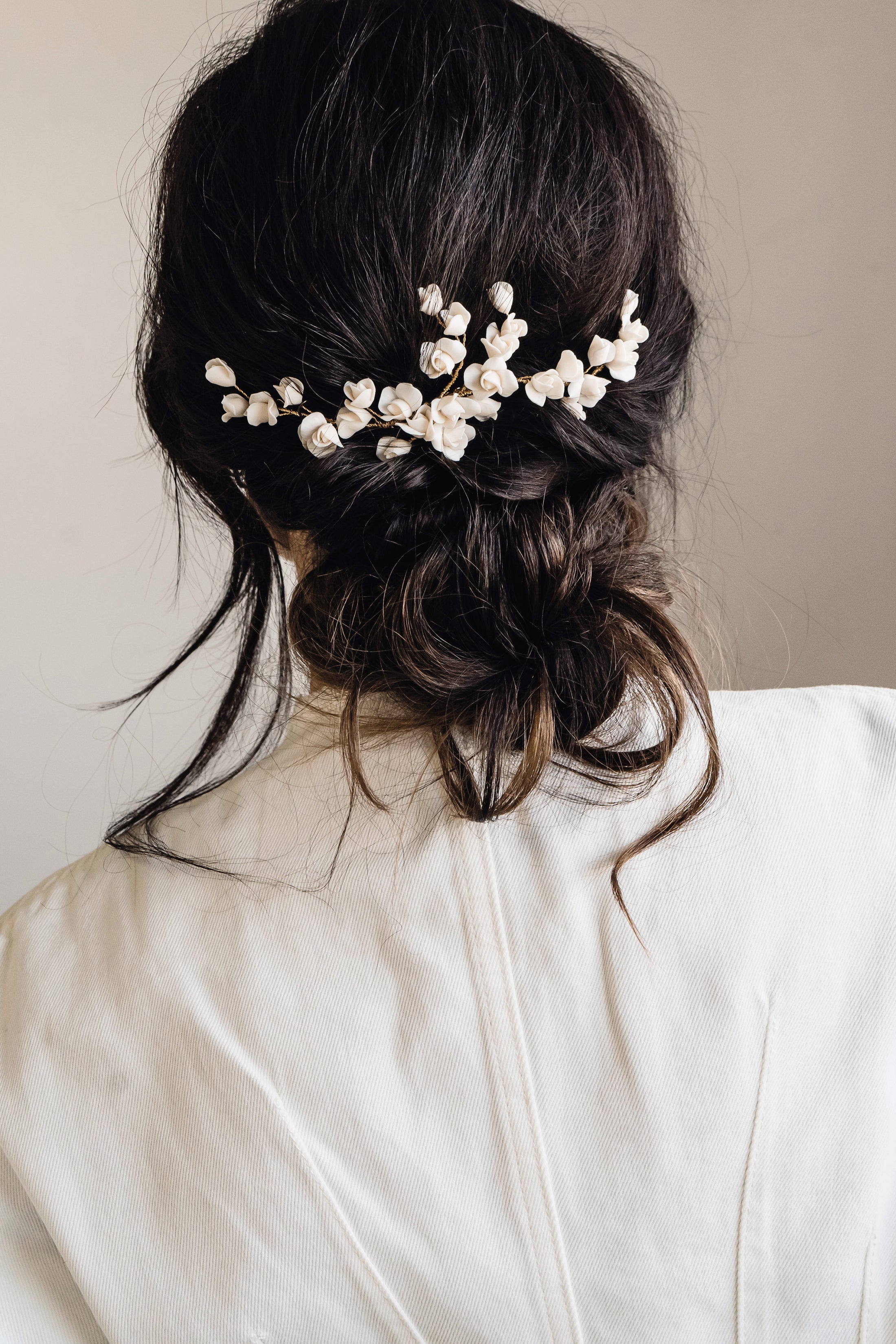 Person with hair styled in an updo adorned with decorative hairpins against a neutral background