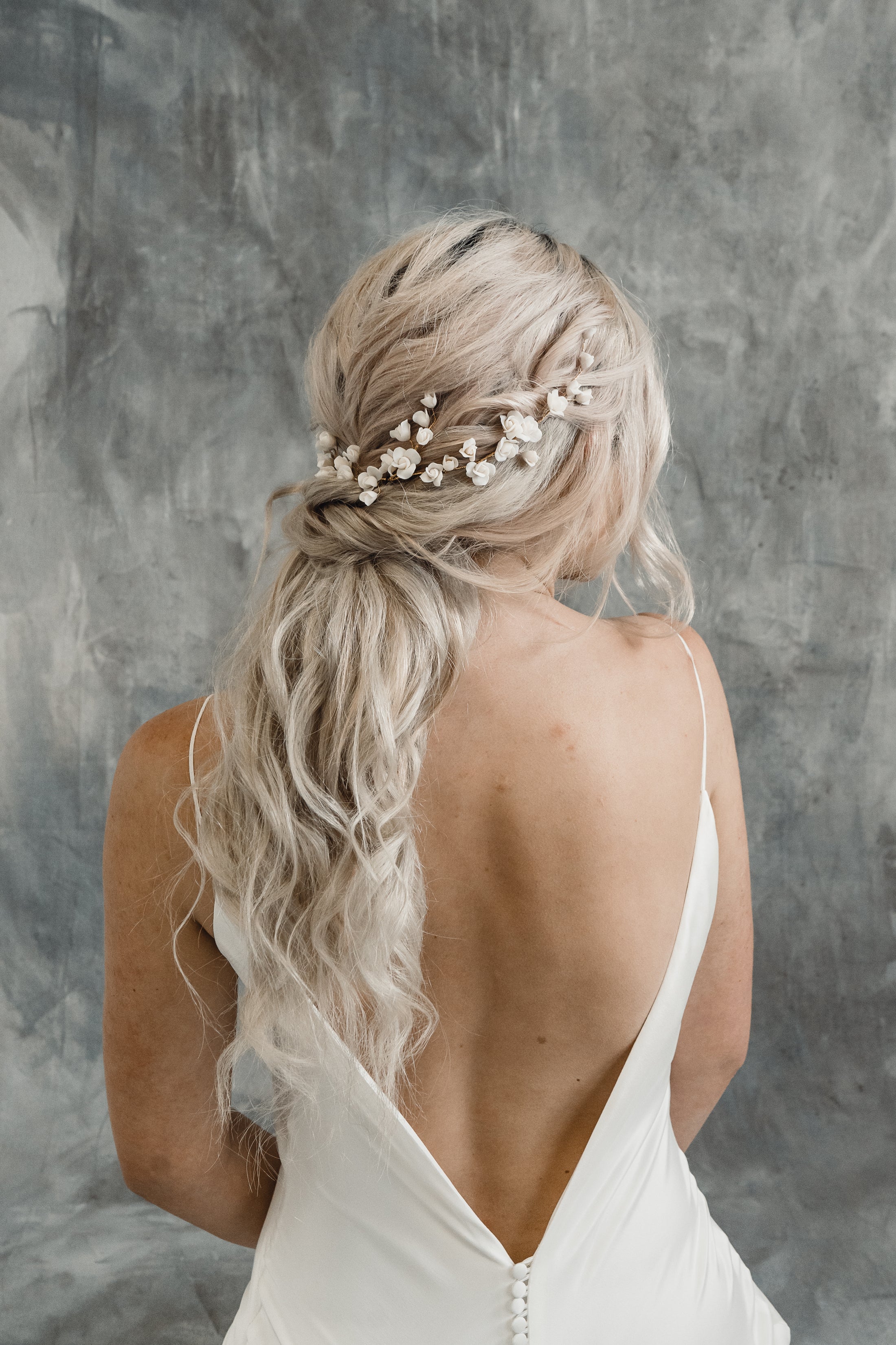 Woman with styled hair featuring flowers against a gray textured background