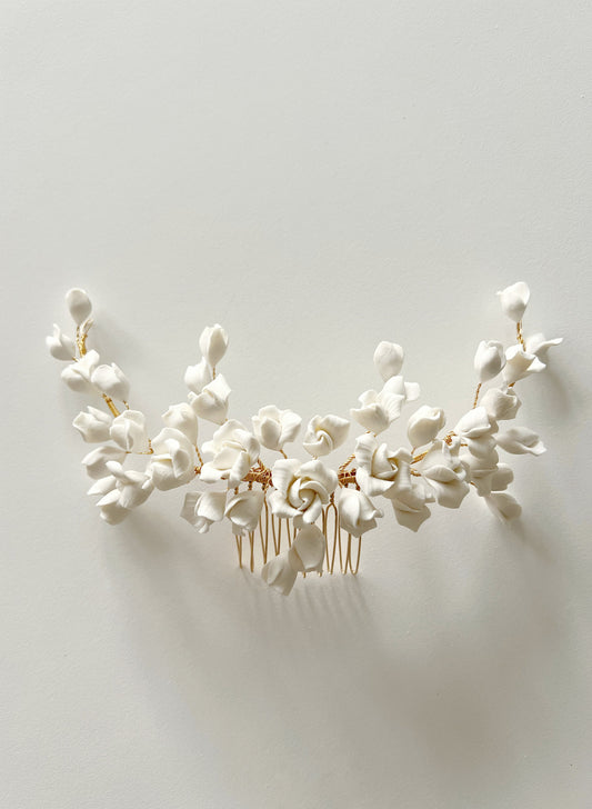 Floral hair comb with white flowers and gold accents on a light gray background