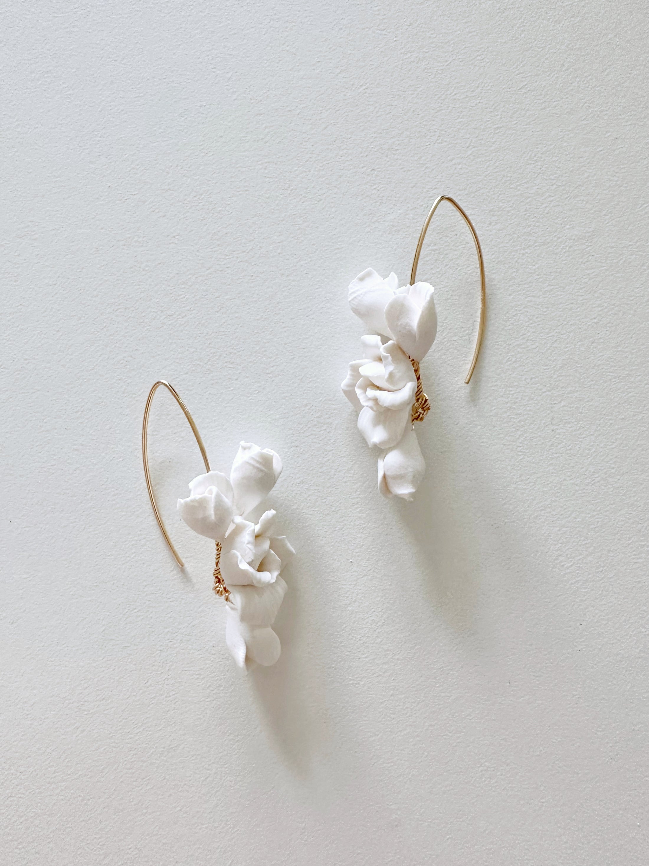 White ceramic earrings with gold accents on a light gray background