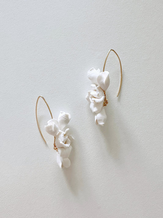White ceramic earrings with gold accents on a light gray background