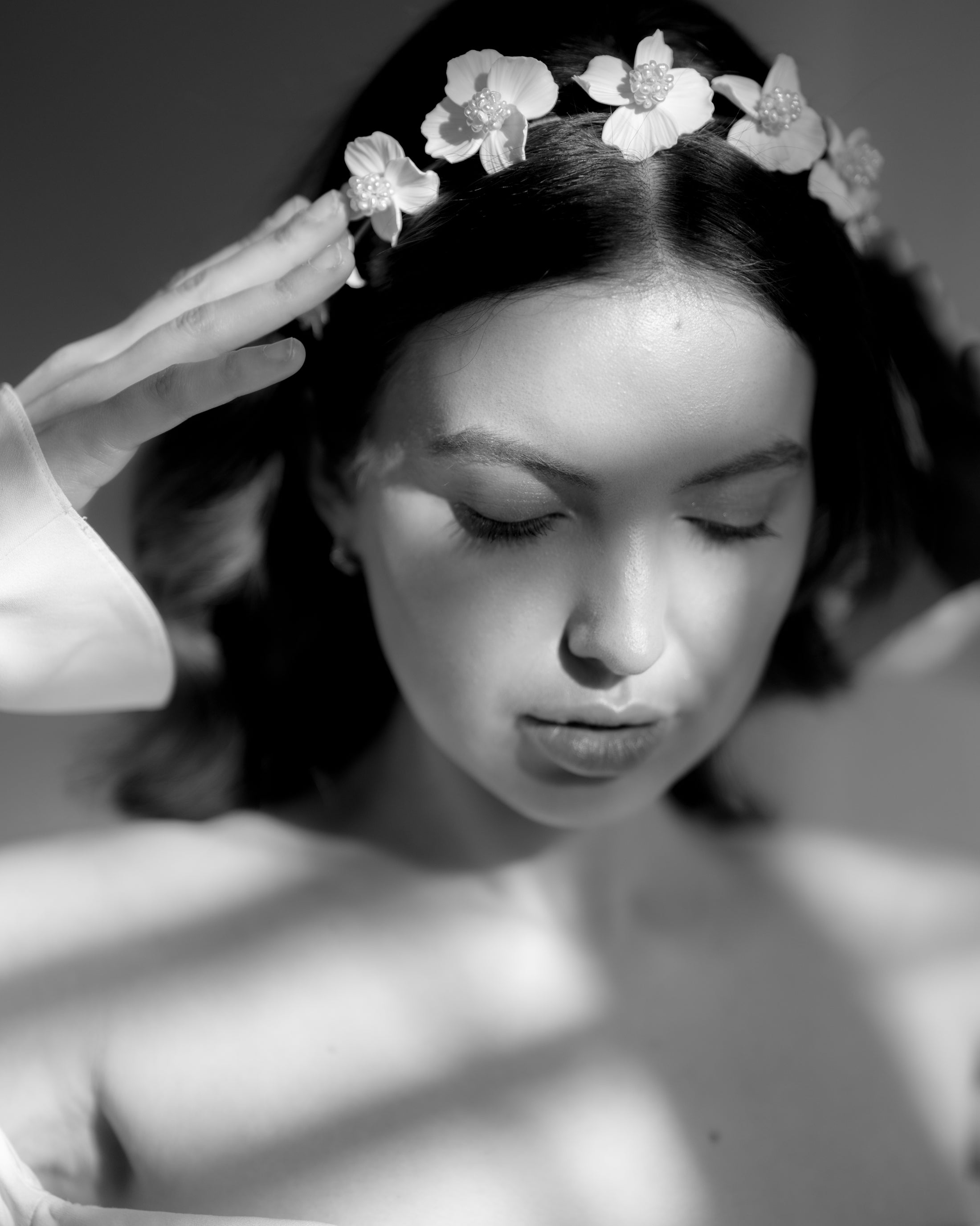 Black and white photo of a woman with a floral headpiece, softly lit.
