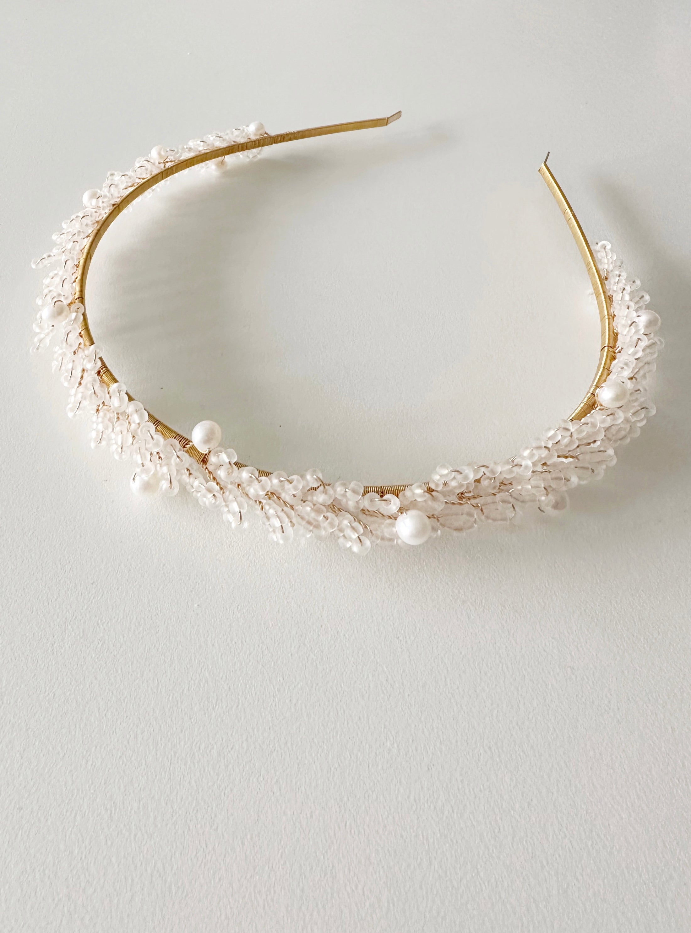 Gold headband with pearls on a light gray background